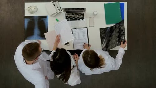 Team of Doctors Looking at Laptop and Analyzing Xray in Medical Office