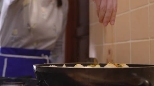 Adding Spices to Pan of Vegetables in Kitchen