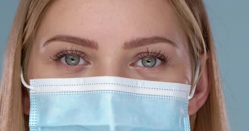 Close Up and Crop Frame of Young Woman Posing in Medical Face Mask. Looking at Camera with Smile