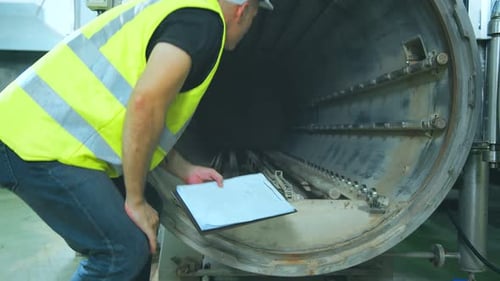 Kaukasischer männlicher leitender Ingenieur, der Sicherheitsuniform trägt, Checklisten für den Handgebrauch, Diagramm, Aktenordner