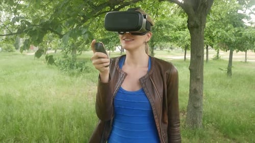 Young Sexy Woman In A Virtual Reality Helmet Uses A Virtual App In The Park