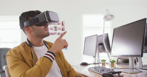 Mixed race man wearing VR headset in creative office
