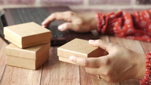 Hands Holding Box While Typing on Laptop