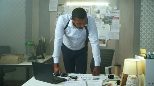 Man Leans Over Desk Examining Case Files