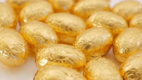 Œufs de Pâques en chocolat enveloppés de papier d'aluminium doré à inclinaison lente 4K 2160p UltraHD - Œufs en chocolat sur whi