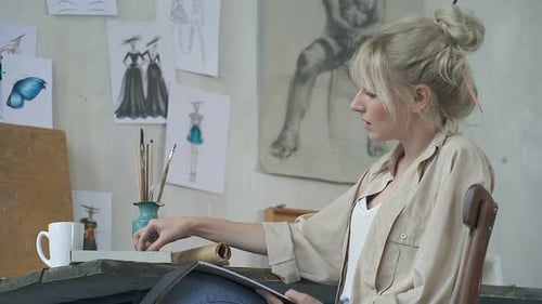 Young Adult Woman Drawing Fashion Sketches in Studio