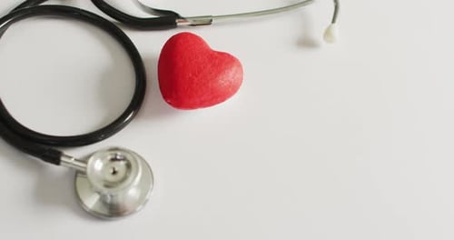 Video of close up of stethoscope with heart on pink background