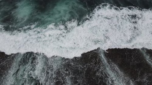 Top down aerial view of giant ocean waves crashing and foaming
