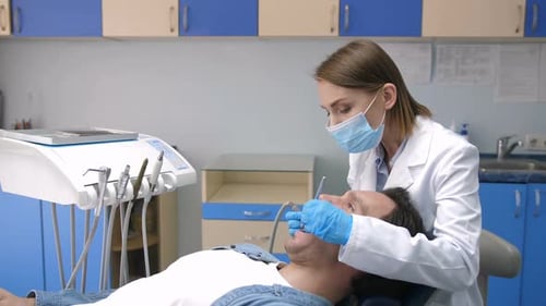 Dentist in Mask Treating Cavity of Patient's Teeth