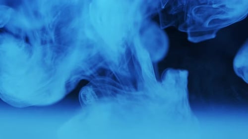 Weiße Tinte fiel auf einem Hintergrund von schwarzen und blauen Farbtönen ins Wasser