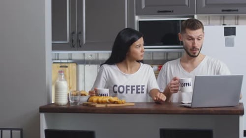 Couple Enjoys Coffee and Laptop in Kitchen