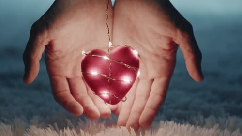 Hands Holding Glowing Heart Shape Tenderly