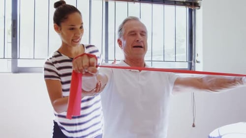 Woman Assists Senior Man Stretching with Resistance Band