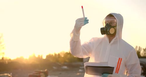 Scientist Examining Test Tube in Contaminated Zone at Sunset