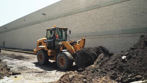Yellow Loader Scooping Dirt at Construction Site