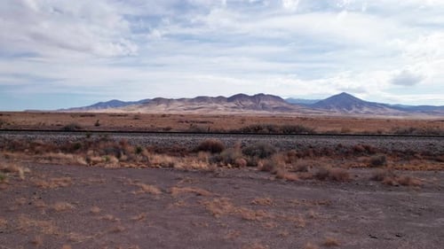 Niedrige Drohnenschüsse rechts von einer Eisenbahnstrecke in der Wüste