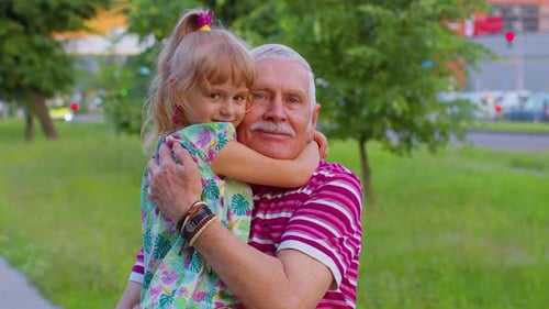 Little Granddaughter Child Embracing Kissing with Her Grandfather in Park Happy Family Relationship