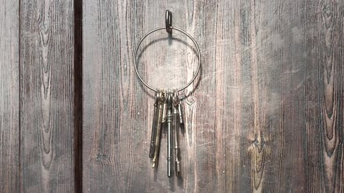 Animation of keyring hanging on a hook with a view at wooden doors nearby. 4KHD