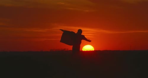 A Boy Is Running Across the Field. The Sun Is Setting Below the Horizon.