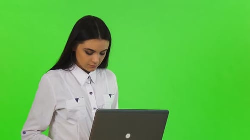 Woman Using Laptop in Front of Green Screen