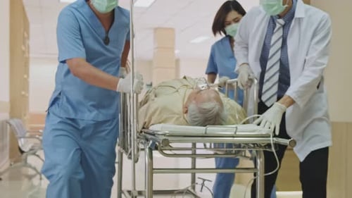 Group of doctor, nurse and surgeon moving seriously injured patient lying on a stretcher in hospital