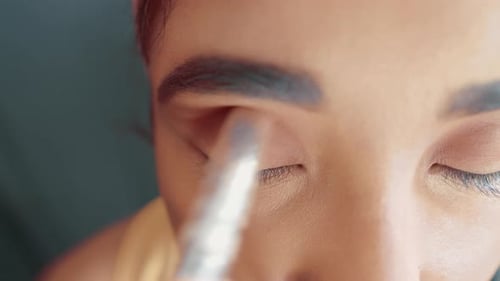 Close up of make up process and putting a eye shadow on woman's eyes with make up brush