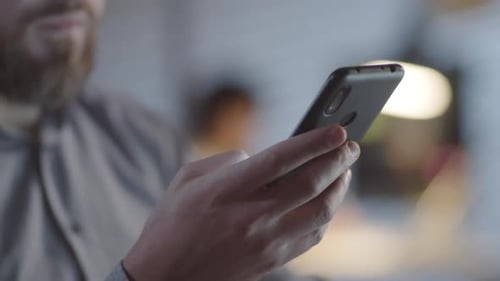 Man with Beard Using Phone in Dark Office