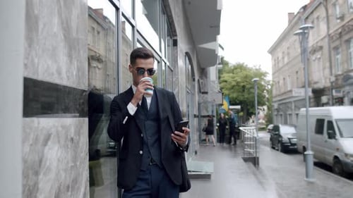 Man in Suit Using Phone on City Sidewalk