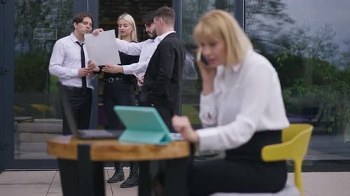 Des collègues discutent du projet alors qu'une femme floue et concentrée parle sur la messagerie téléphonique