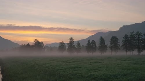 Misty Sunrise Over Rural Grassy Mountain Landscape