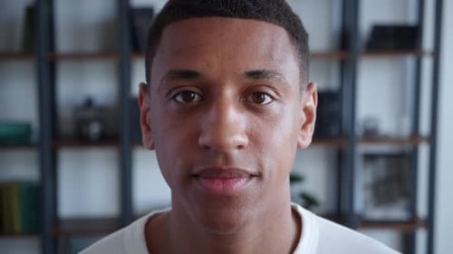 Confident Portrait of Young African American Guy Looking to the Camera at Home Office Background