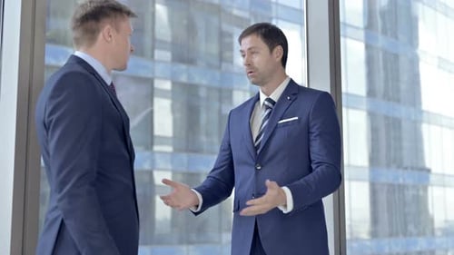 Upset Two Middle Aged Businessmen Having Arguments Against Boardroom Office Window