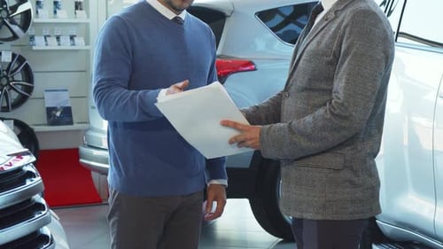 Men Discussing Paperwork and Shaking Hands at Dealership