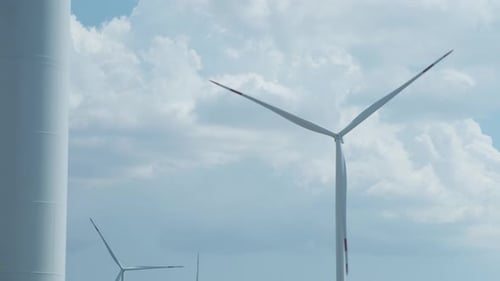 Windturbinen erzeugen Strom gegen flauschige Wolken