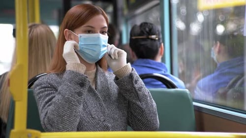 Woman Puts On Face Mask On Bus