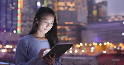 Woman Using Tablet in a City at Night