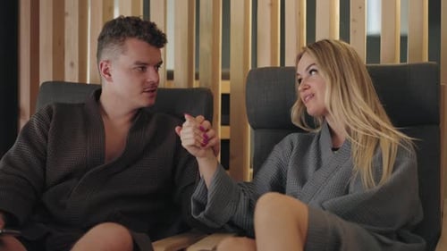 Happy Honeymooners in Spa Hotel Resting and Relaxing in One Zone Wearing Gowns Chatting Together