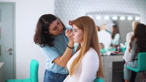 Aesthetician Applying Makeup to a Woman's Eyebrows in Salon
