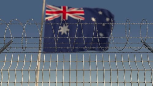 Waving Australian Flag Behind Barbed Wire Security Fence