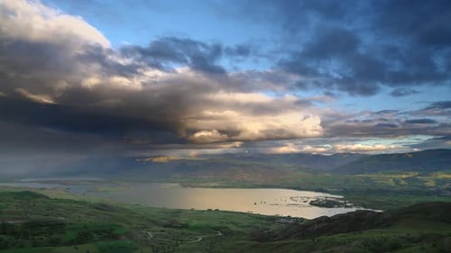 Storm Clouds and Rain Approaching to Lake Geography Surrounded by Hilly Meadows