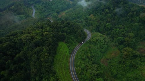 Aerial view over a winding road in the mountains of a tropical forest, Thailand.