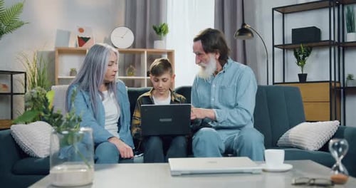 Grandparents and Child Using Laptop on Couch