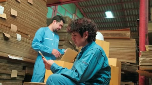 Two workers and colleagues check shipment orders stock at parcels warehouse.