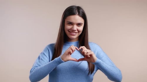 Smiling Woman Makes Heart Shape with Hands