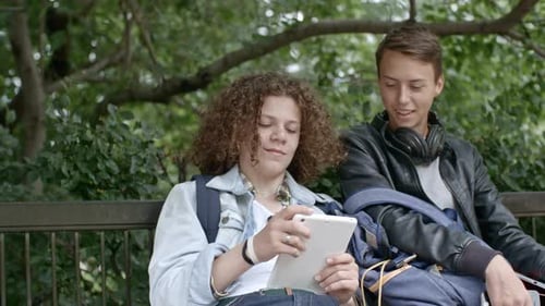 Young Adults Using Tablet on Park Bench
