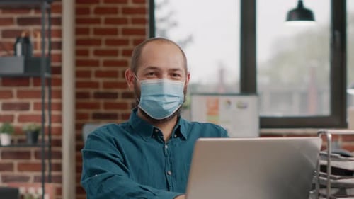 Portrait of Business Man Wearing Face Mask and Using Laptop