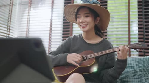 Young Woman Singing and Playing Ukulele at Home