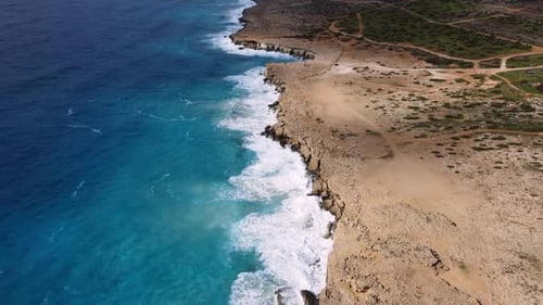 Sea Washes the Rocky Shore Above Aerial Shot Flying Over Coastline Cliffside with Blue Pure Water