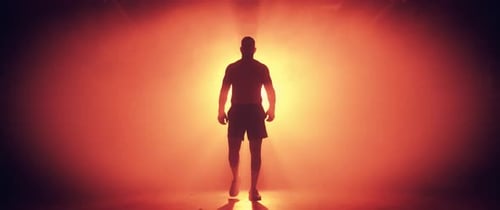 Silhouetted Man Walking in Dramatic Smoky Interior