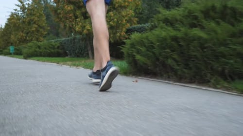 Rear View Male Feet of Sporty Man Running Along Sidewalk at Summer Day
